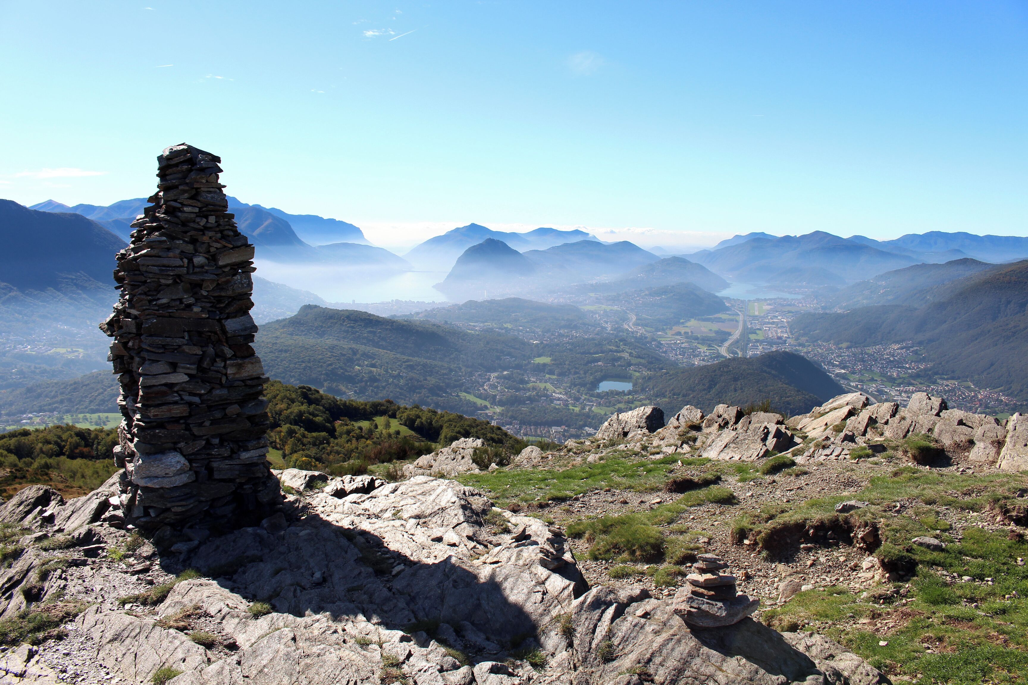 Vom Gipfel des Monte Bigorio (1188m.ü.M.) geht der Fernblick zum Lago di Lugano. Auf der rechten Bildseite sieht man die Orte Bedano, Gravesano, Bioggio und Agno. Daneben verläuft die Autobahn zwischen Milano und Gotthard. In der Bildmitte ist der Lago d'Origlio zu sehen.