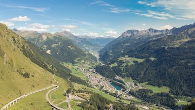 Un paysage montagneux avec une route sinueuse, une petite ville et un lac.