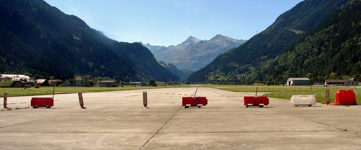 A mountainous landscape with a runway and red barriers.