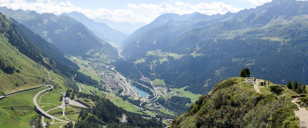 A mountainous landscape with a winding road, a valley, and a small settlement.