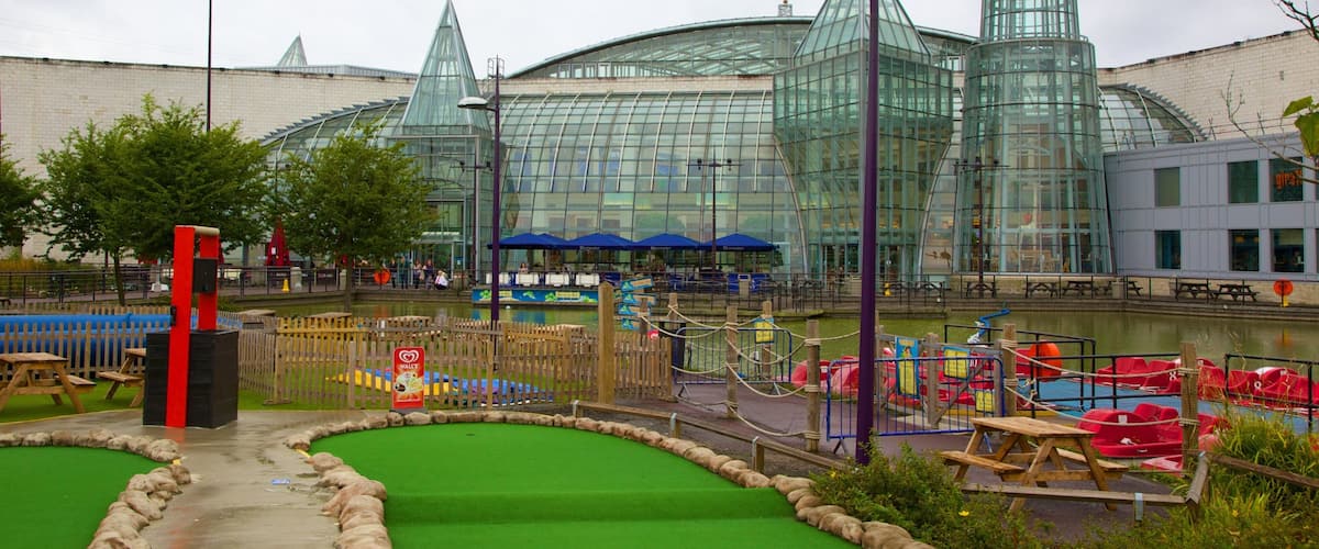 A miniature golf course with a modern glass building in the background.