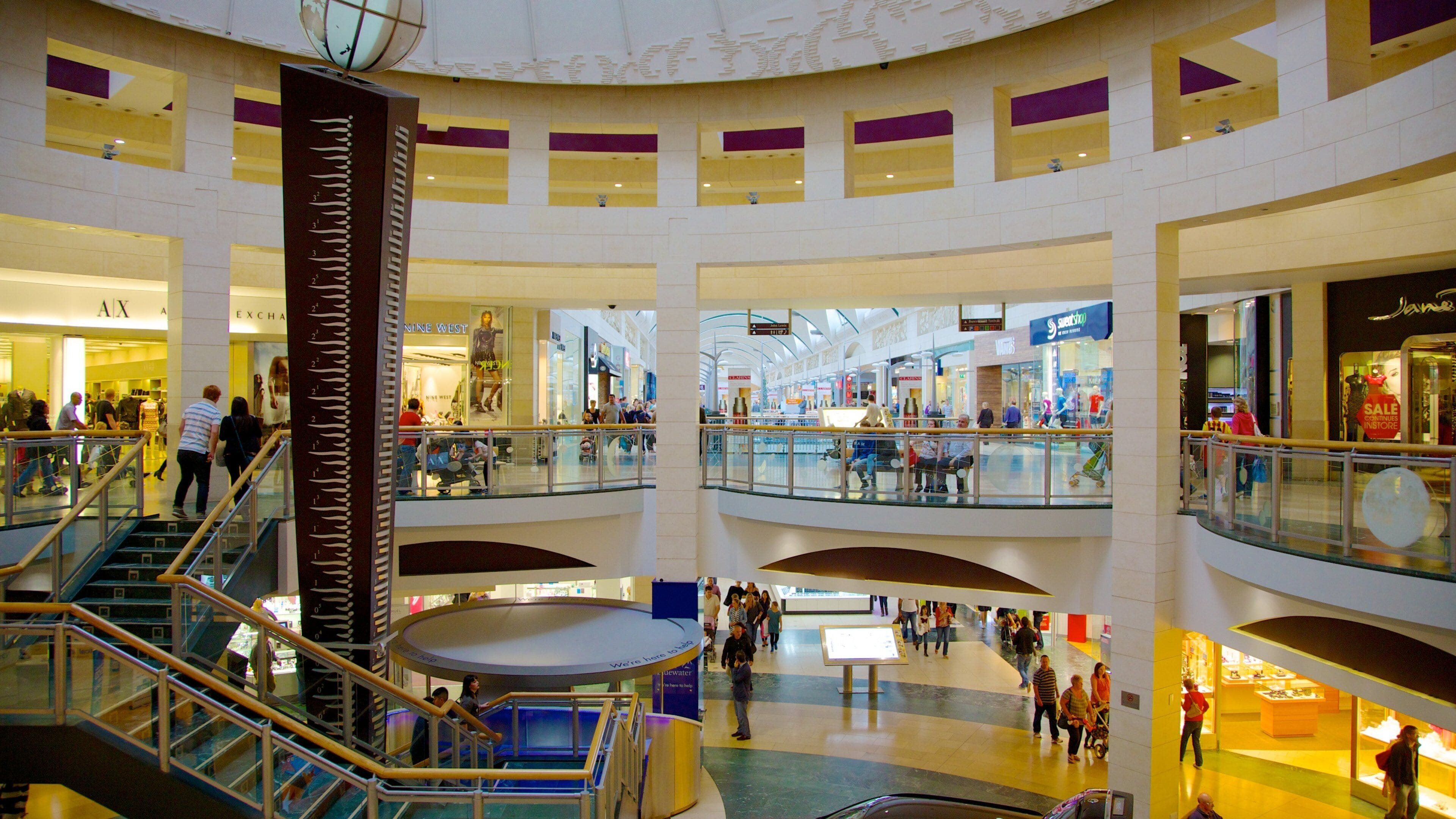 Een meerlaags winkelcentrum met glazen balustrades, roltrappen en diverse winkels.