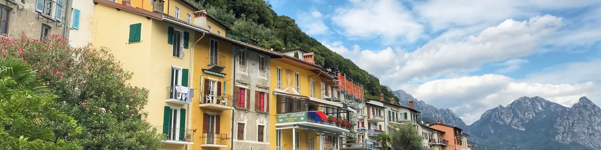 Un pintoresco pueblo a orillas de un lago, con edificios coloridos, barcos y montañas al fondo.