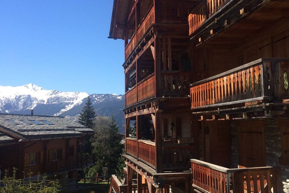 Una xalet de fusta amb múltiples balcons davant d'un paisatge de muntanya.