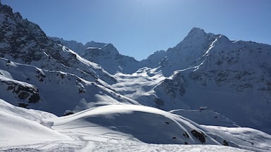 A snow-covered mountain range with a clear sky and the sun shining brightly.