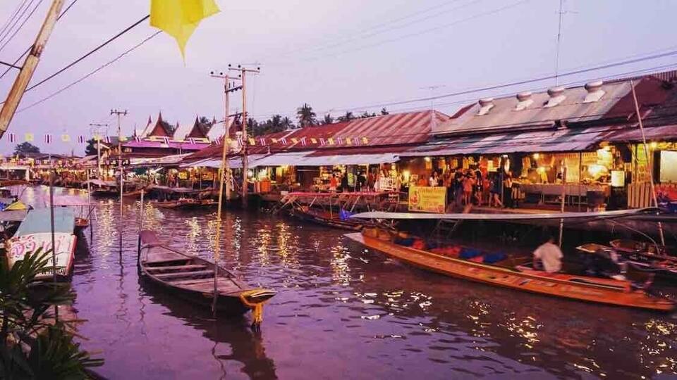 A riverside market with boats and canopies.