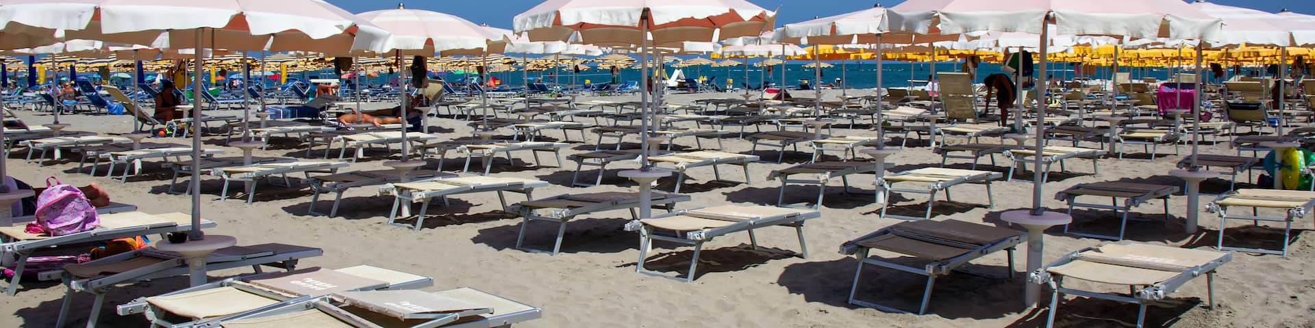 A beach with rows of sunbeds and umbrellas.