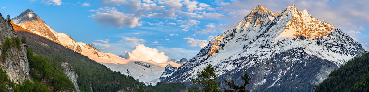 Alpine mountain landscape above Val Herens in Switzerland at sunset with peaks covered by snow and a very big cloud