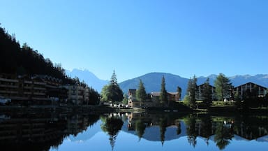 Un lago tranquilo que refleja edificios y montañas.