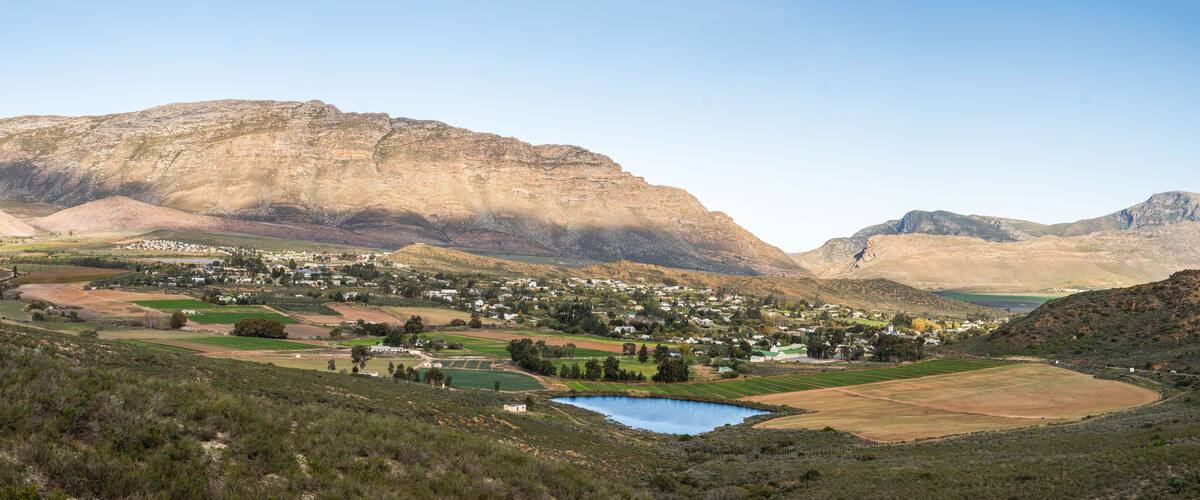 A town nestled in a valley with a lake and mountains in the background.