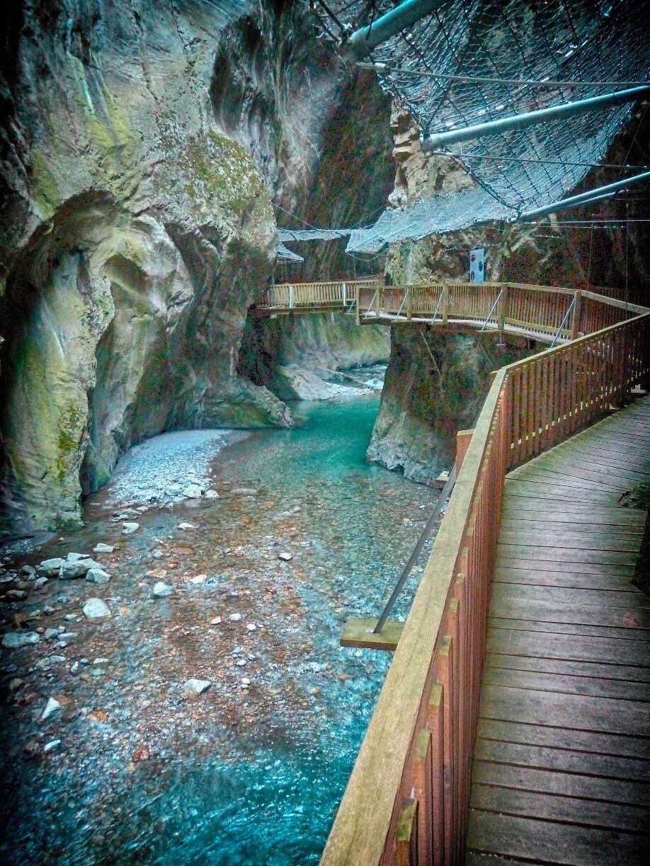 A wooden bridge over a turquoise river in a rocky gorge.