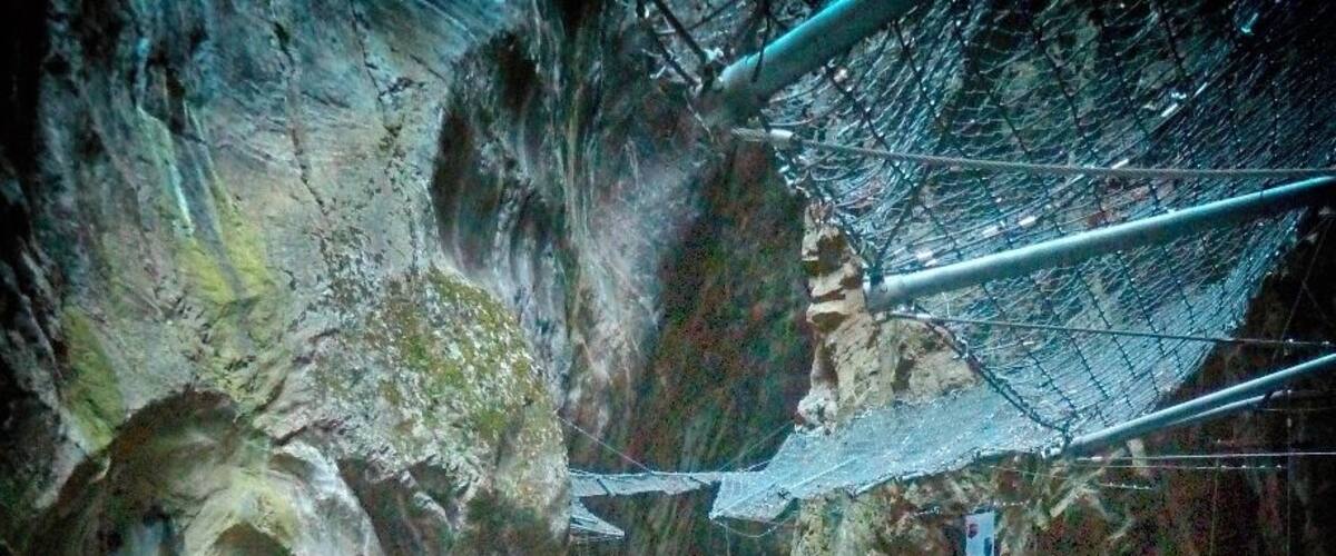 A wooden bridge over a turquoise river in a rocky gorge.