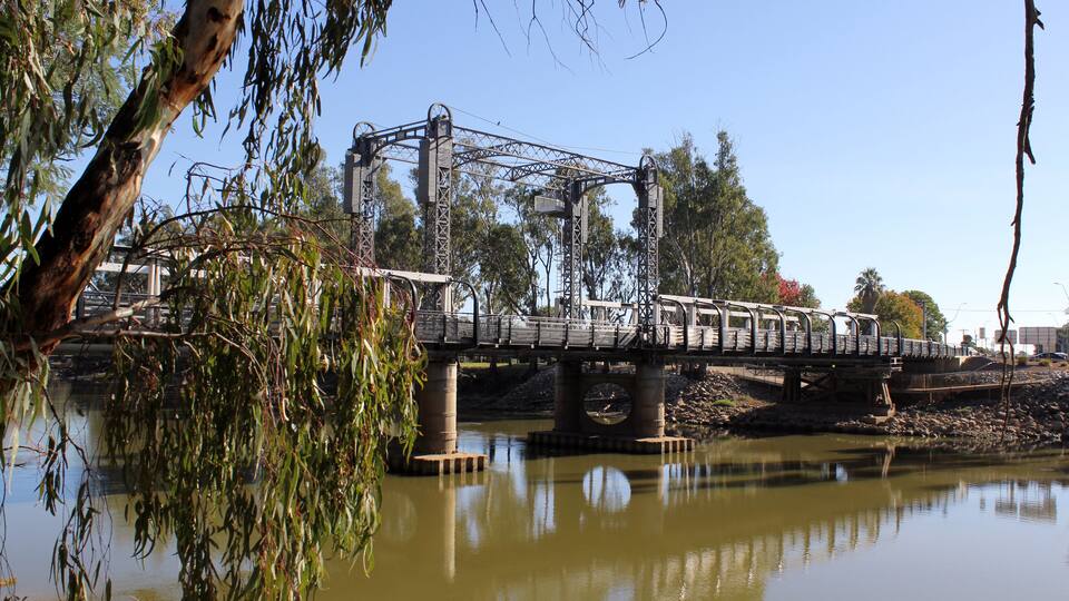 A bridge over a river with trees and a clear sky.