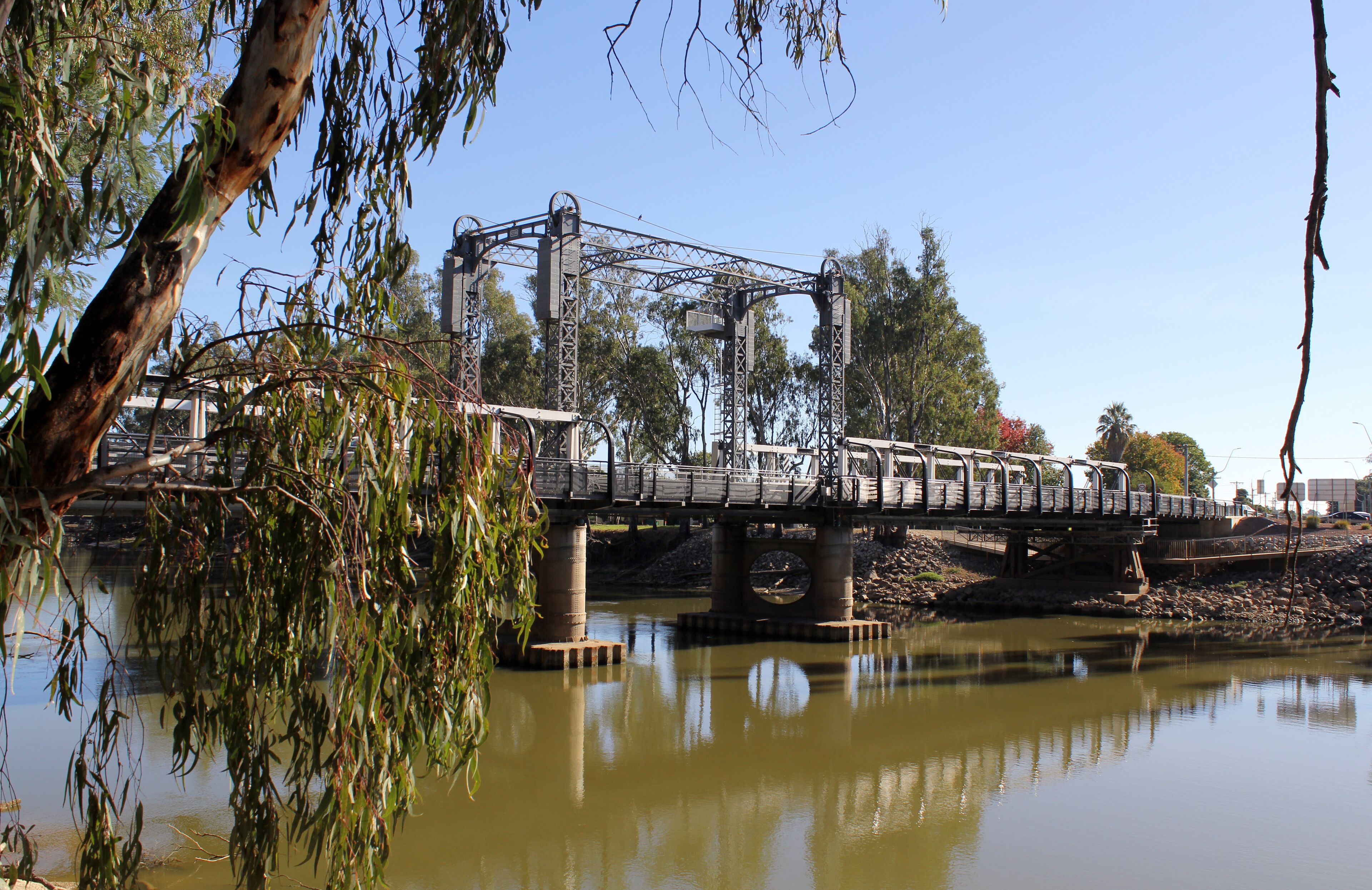 A bridge over a river with trees and a clear sky.