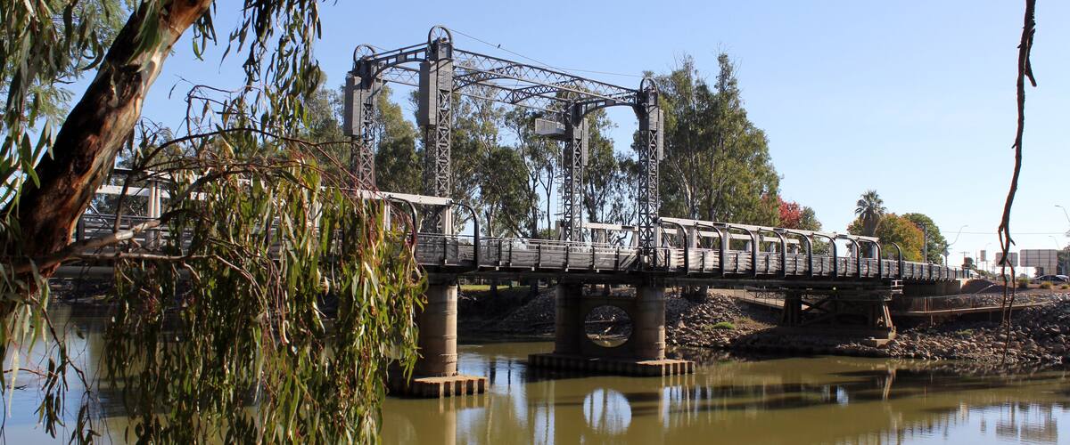 A bridge over a river with trees and a clear sky.