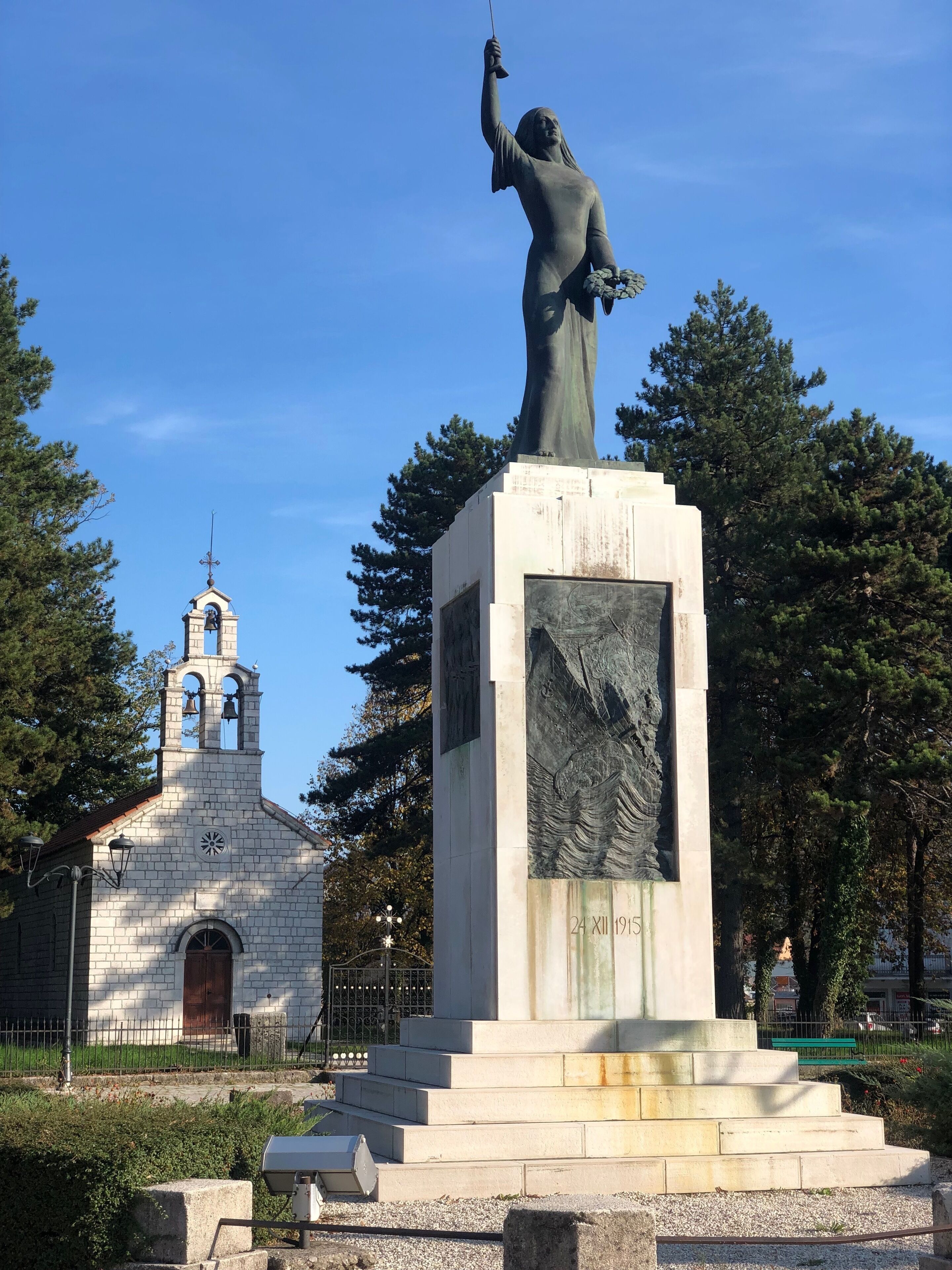 A statue of a woman holding a fish, with a church in the background.