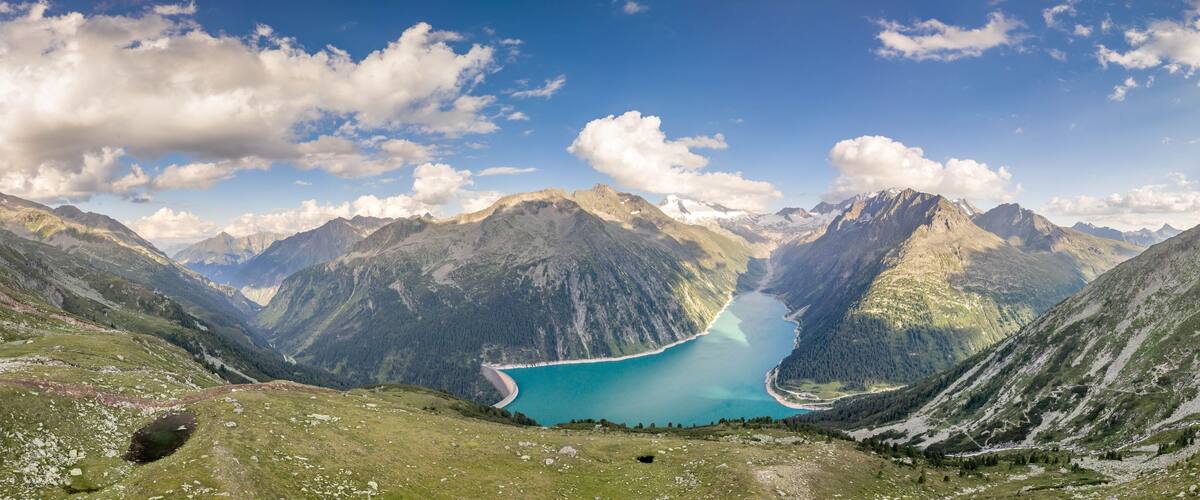 A mountainous landscape with a turquoise lake surrounded by rugged peaks and green valleys.