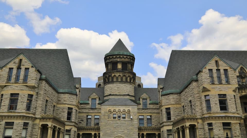 A large stone building with a central turret and multiple windows.