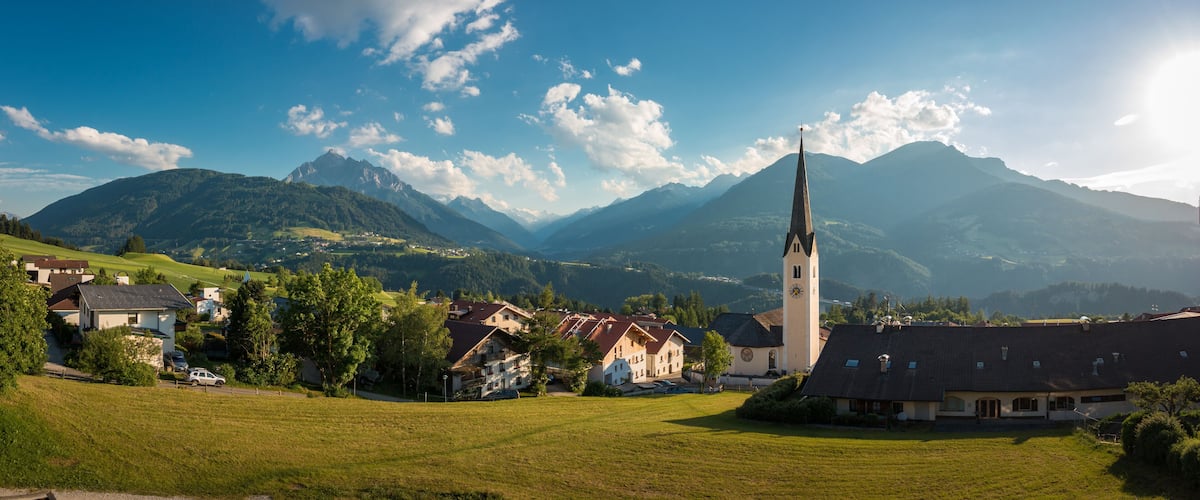 A village with a church, houses, and mountains in the background.