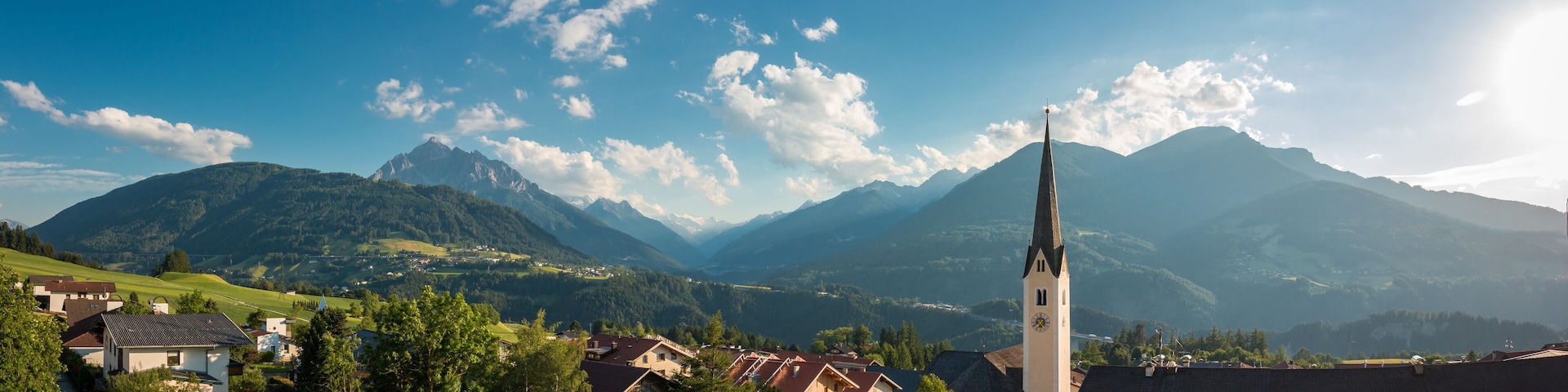 A village with a church, houses, and mountains in the background.