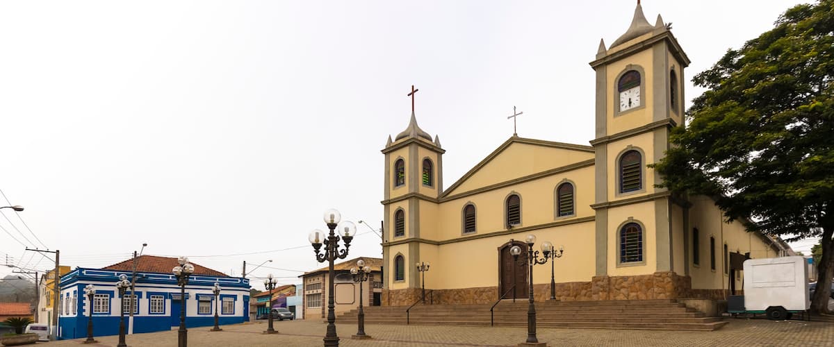 Una iglesia con una torre de reloj y un edificio azul al frente.