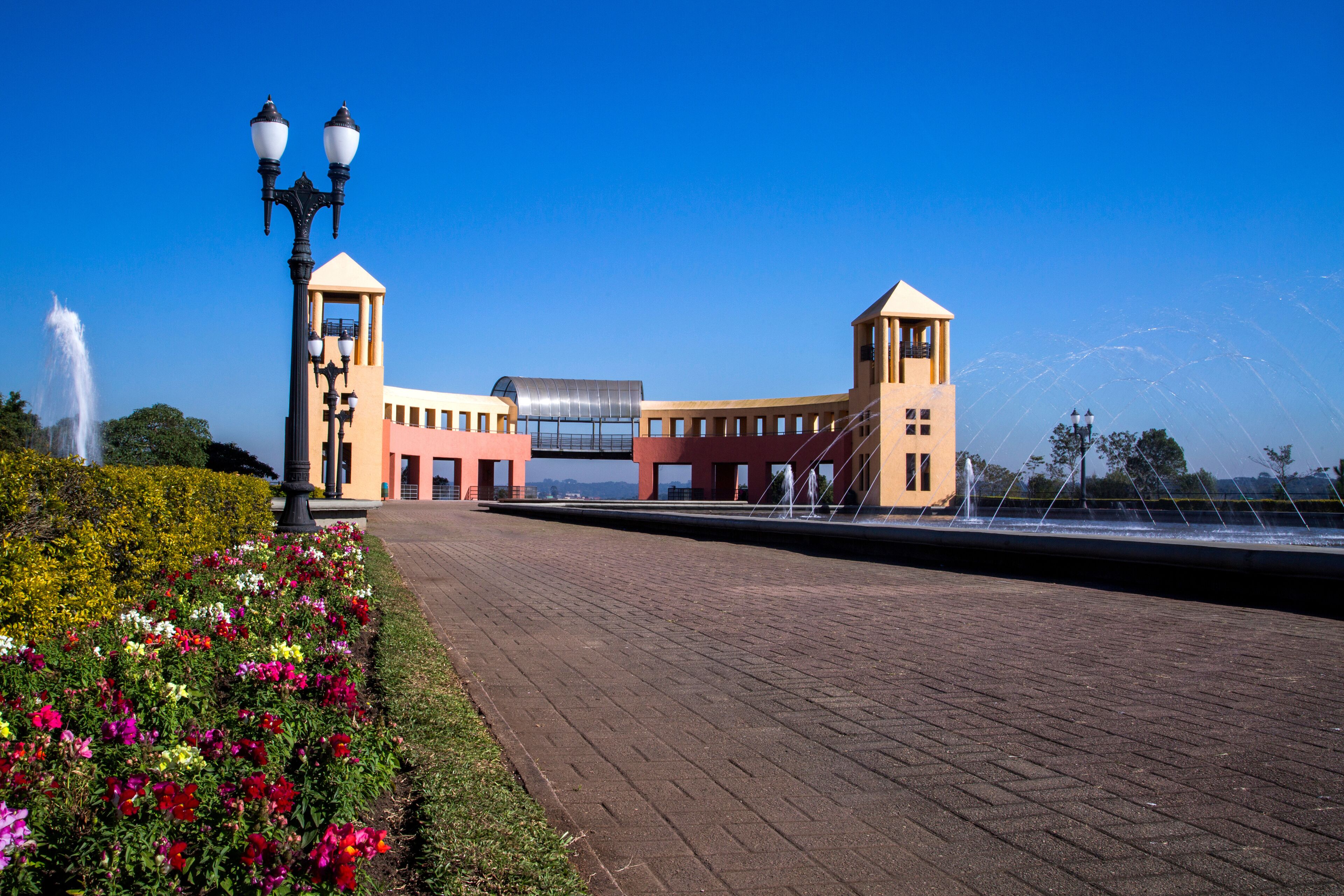 Un paseo marítimo con una fuente, un farol y un edificio de techo característico.