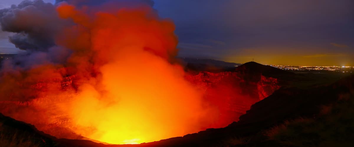 A volcanic crater with glowing lava at night.