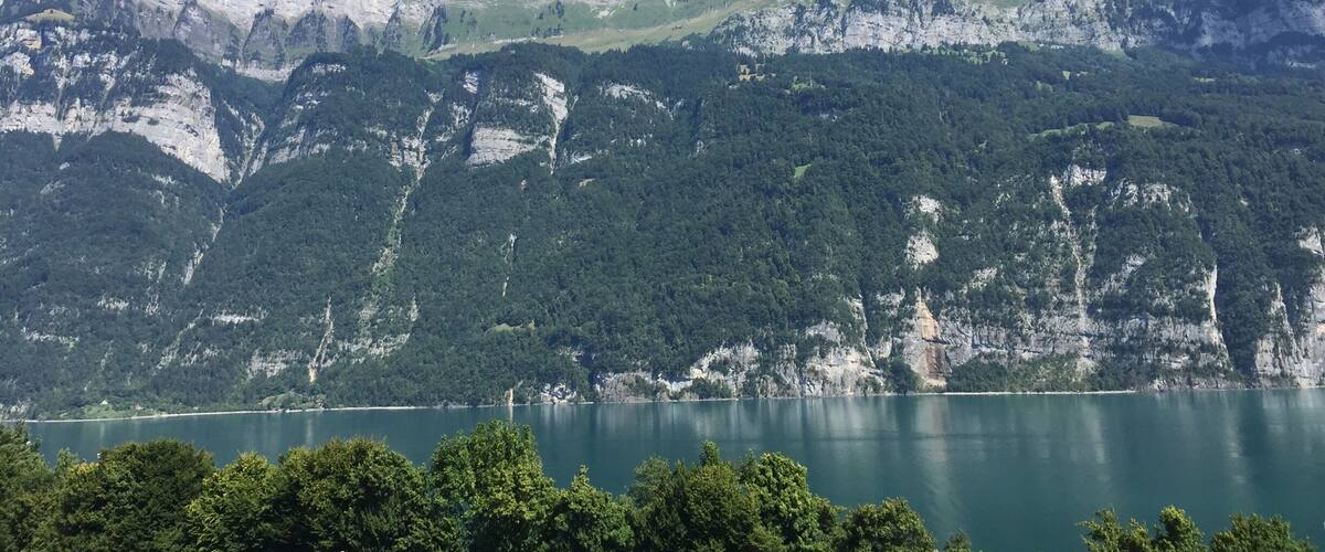 A mountain range with a lake in the foreground and a clear blue sky.