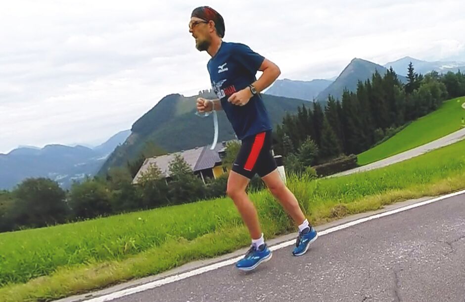 A runner on a road with mountains in the background.