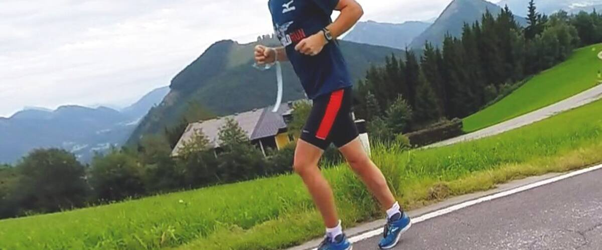 A runner on a road with mountains in the background.