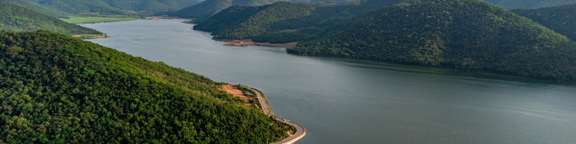 Muak Lek reservoir in Saraburi from aerial bird eye view. Beautiful unseen nature at Muak Lek dam with roadway beside with water and tree hill.