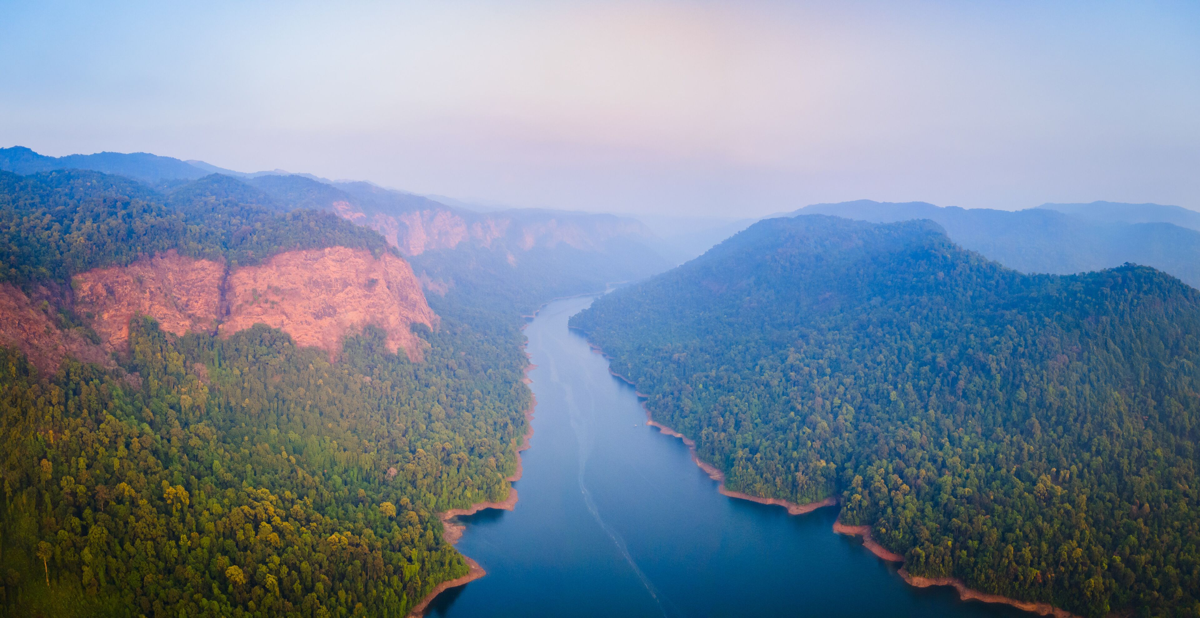 A river winding through a forested valley with mountains on either side.