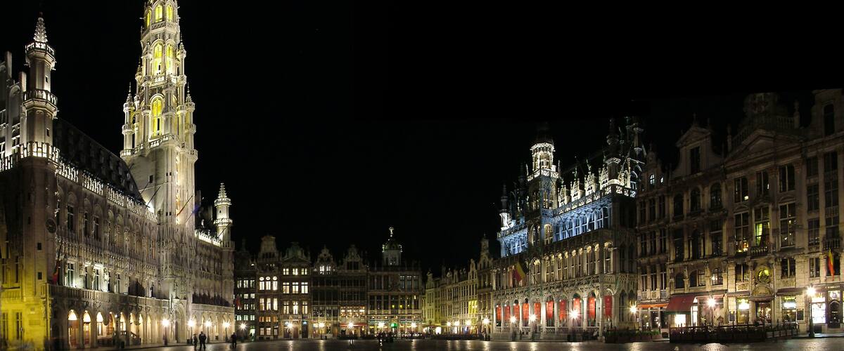 A historic square with ornate buildings and a prominent tower at night.