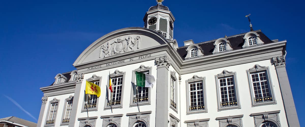 A historic building with a clock tower and flags.