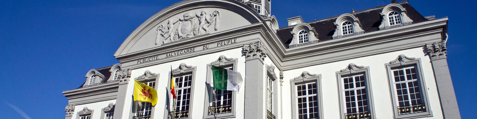 A historic building with a clock tower and flags.