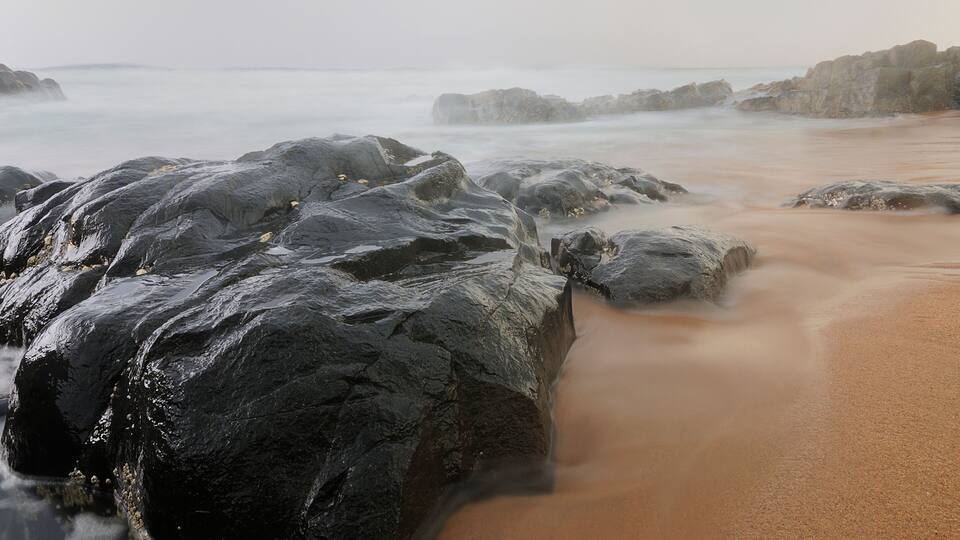 A rocky beach with waves crashing against the shore.