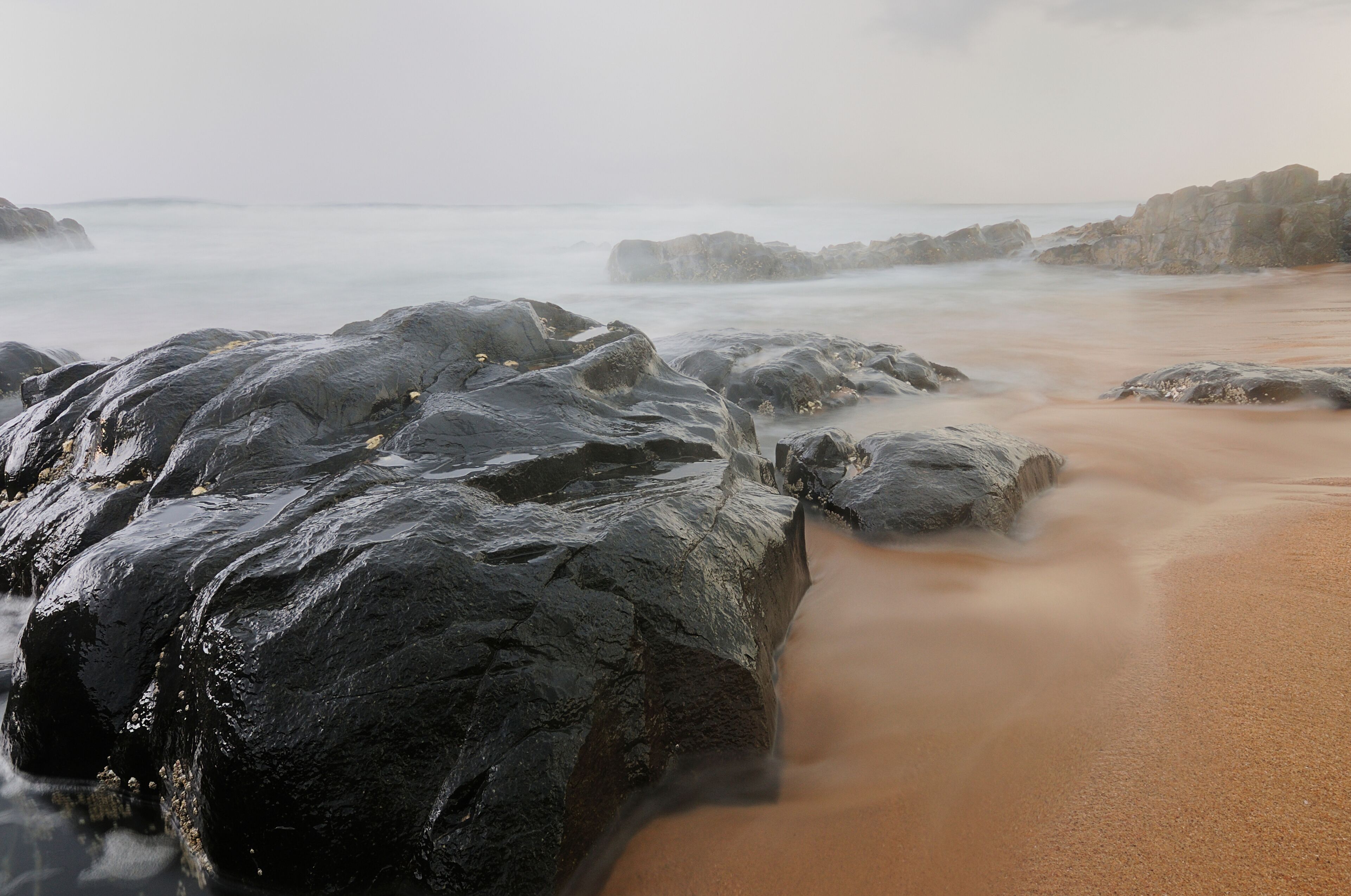 A rocky beach with waves crashing against the shore.