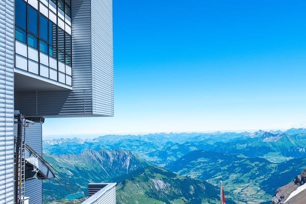 A modern building with large windows overlooking a mountainous landscape.