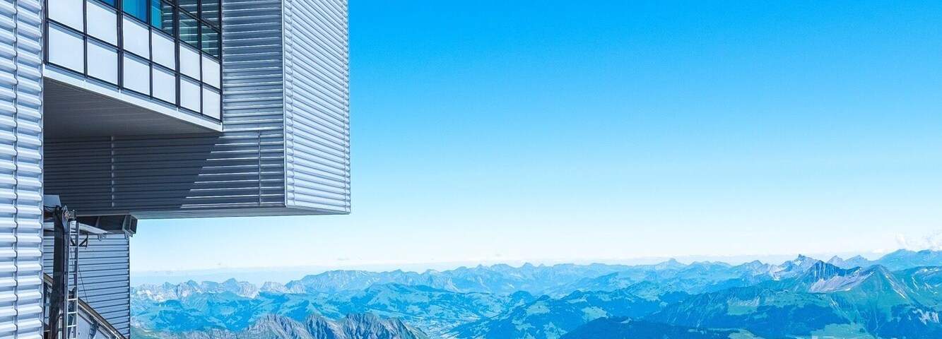 Un edificio moderno con amplios ventanales que dan a un paisaje montañoso.