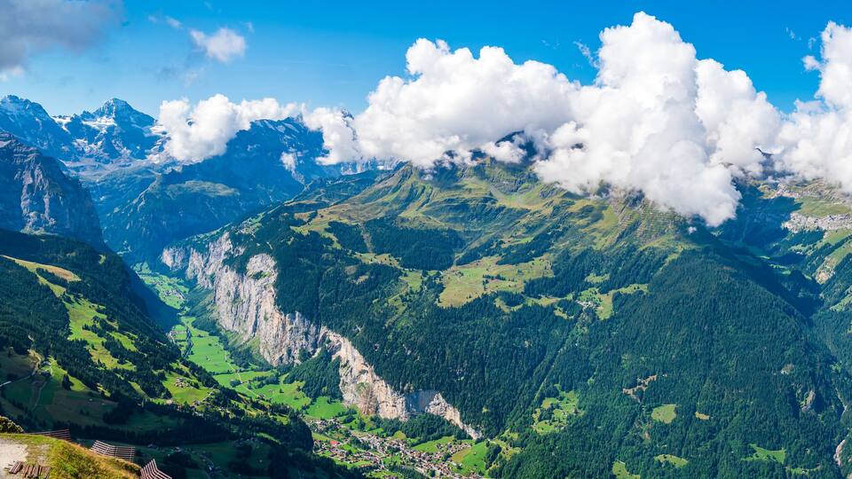 A mountainous landscape with a valley, a river, and a small settlement.
