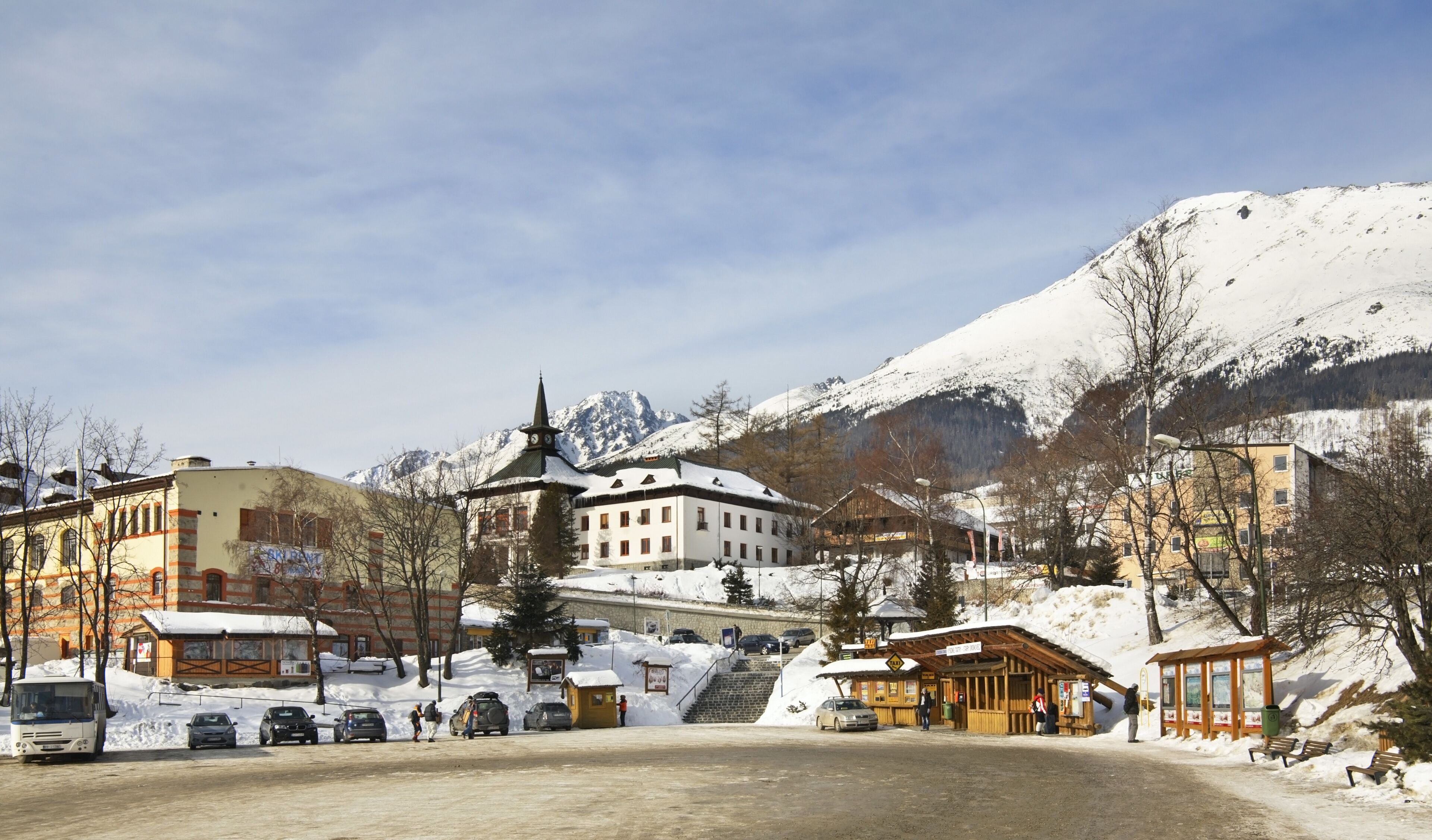 A snowy mountain town with a church, a bus, and a wooden shelter.