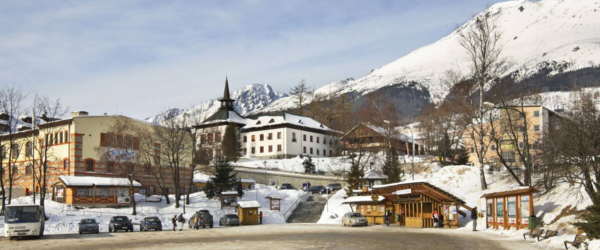 A snowy mountain town with a church, a bus, and a wooden shelter.