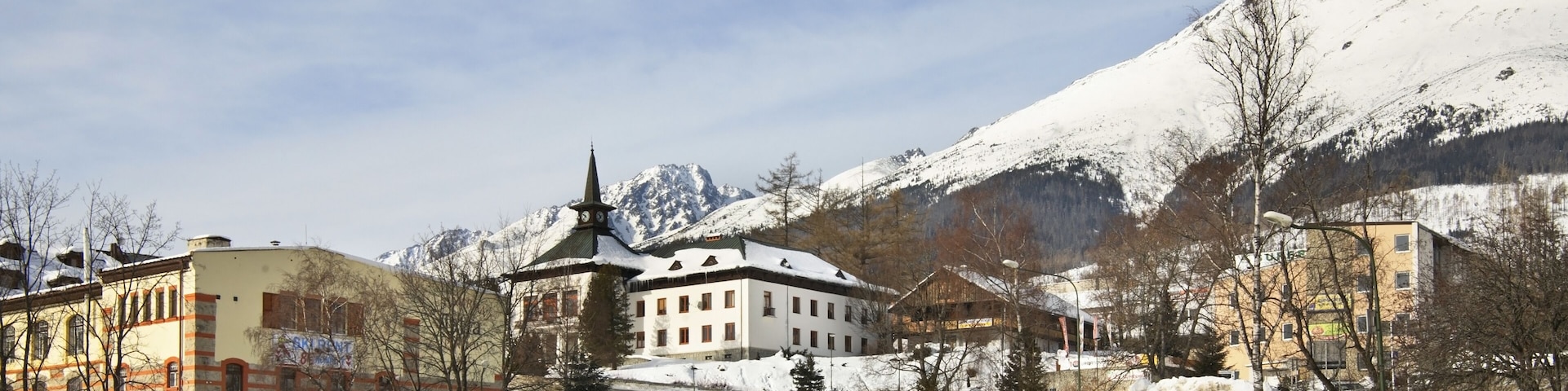 A snowy mountain town with a church, a bus, and a wooden shelter.