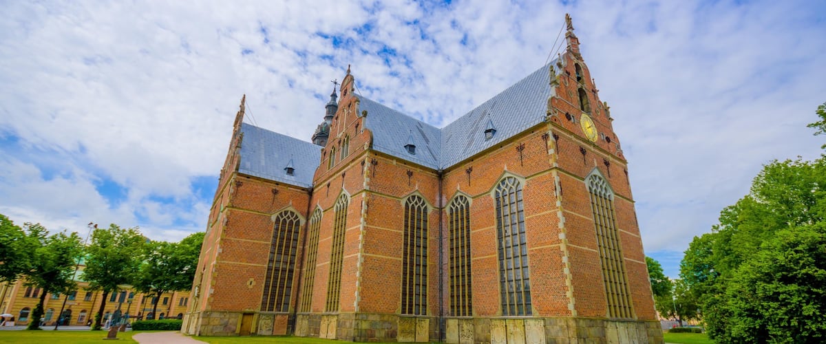 A large brick church with a clock tower and tall spires.