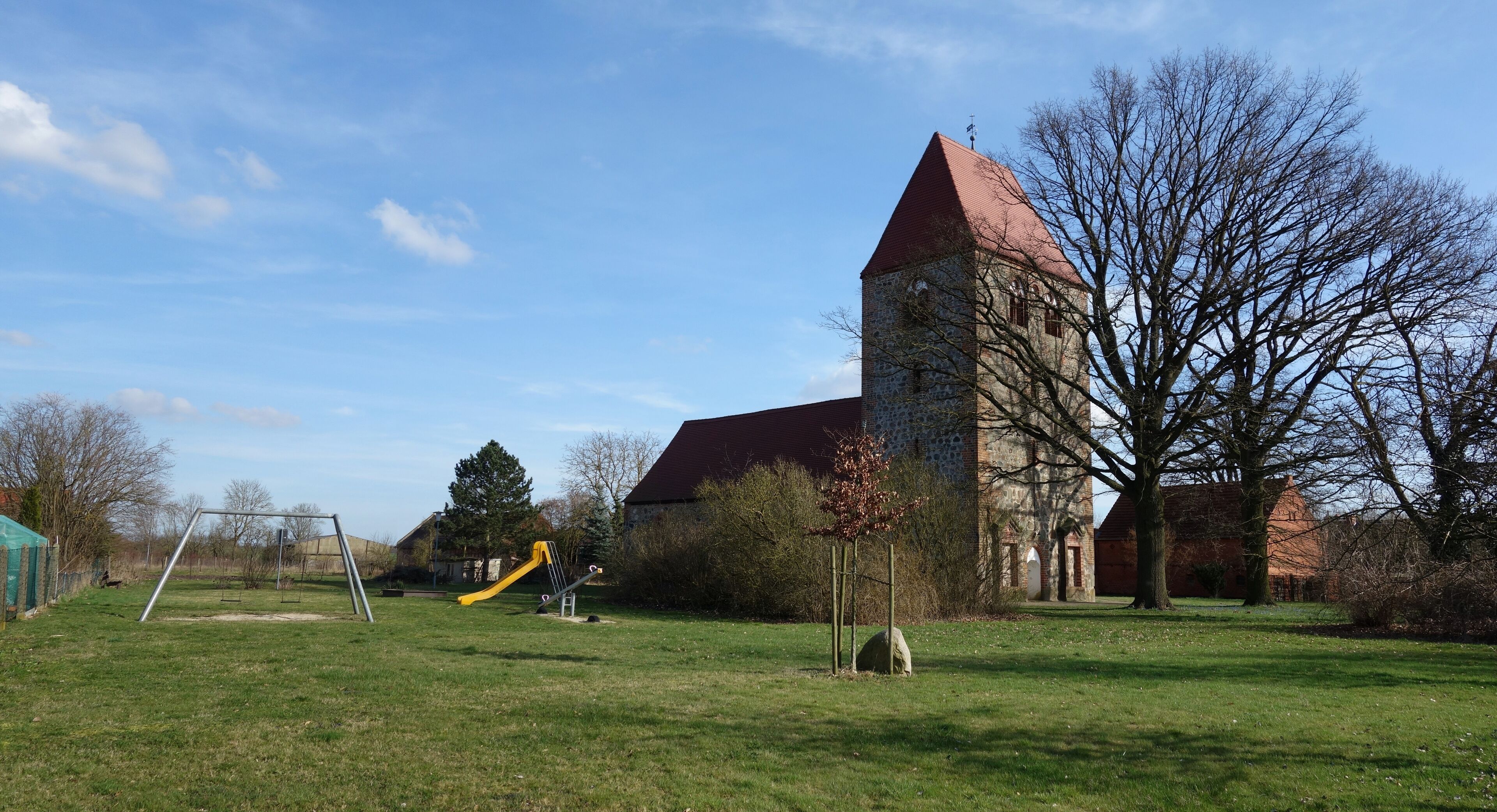 A grassy field with a playground and a stone tower.
