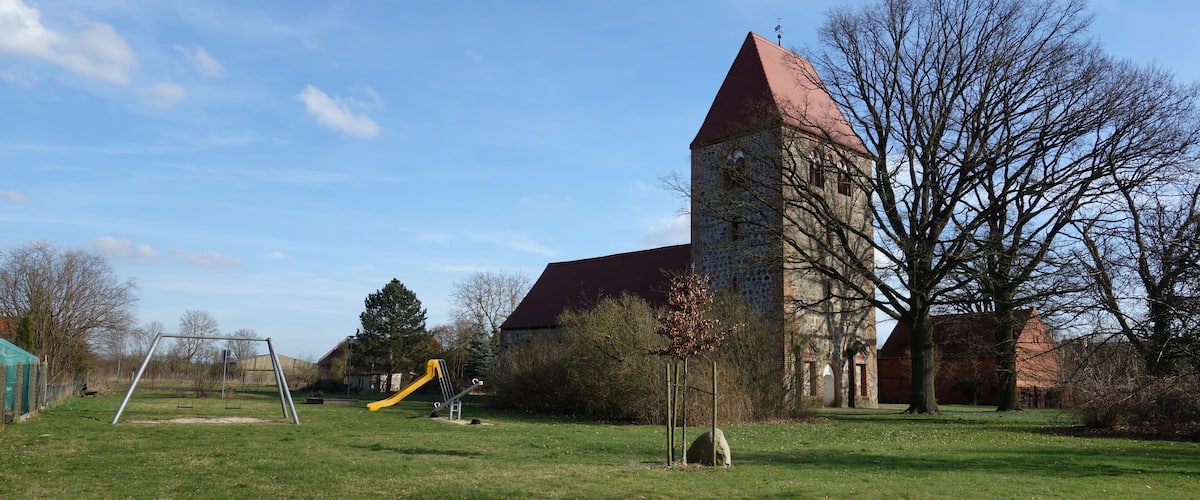 A grassy field with a playground and a stone tower.