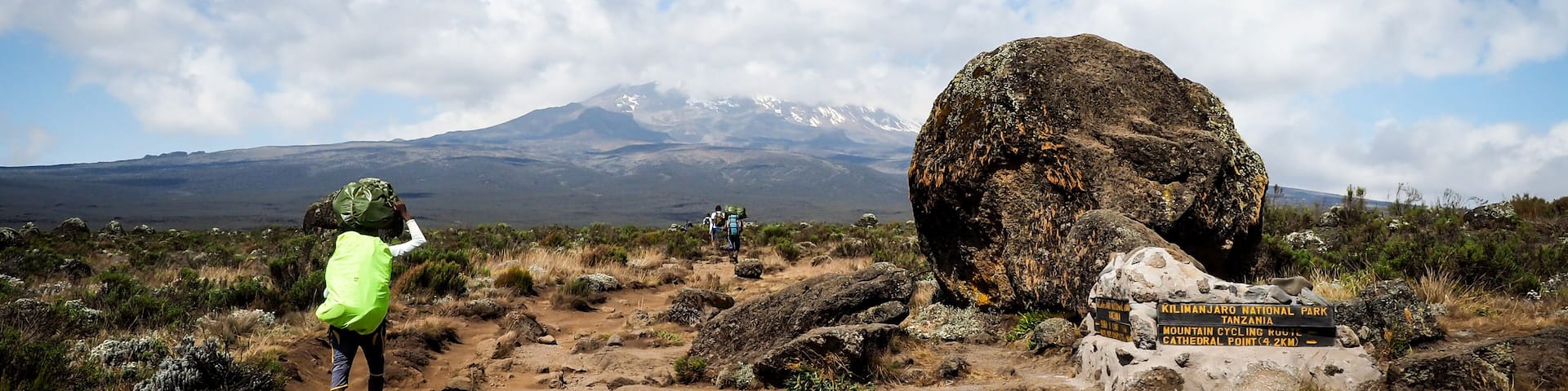 guides porters and sherpas carry heavy sacks as they ascend mount kilimanjaro the tallest peak in africa.