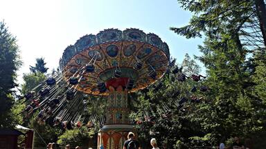 A colorful amusement ride with a decorative canopy and passengers seated in swings.