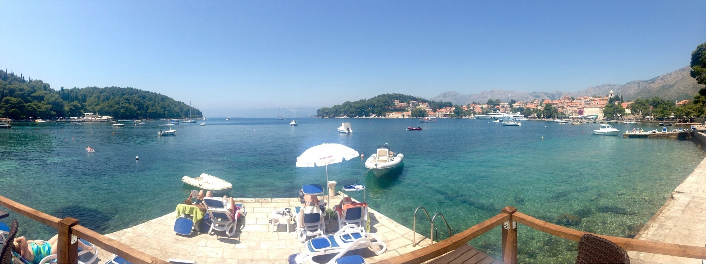 A marina with boats, clear water, and a town in the background.