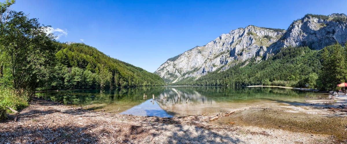 A serene lake surrounded by dense forests and a prominent mountain.